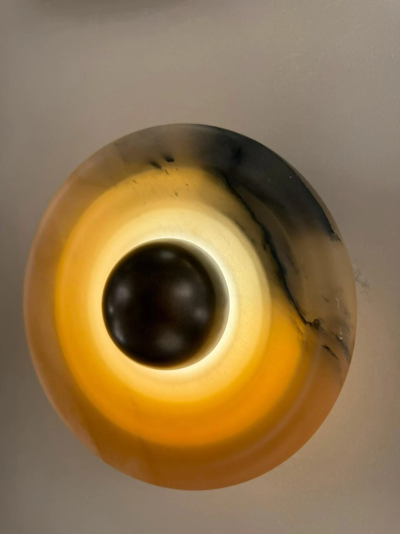 Round illuminated alabaster wall light with dark central cap