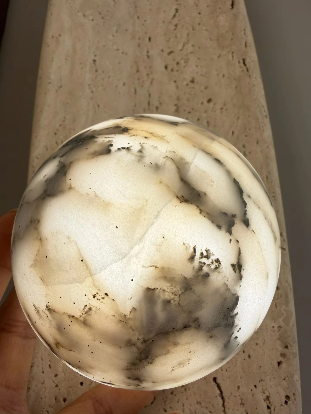 Close-up of a glowing round alabaster shade with grey and dark veining