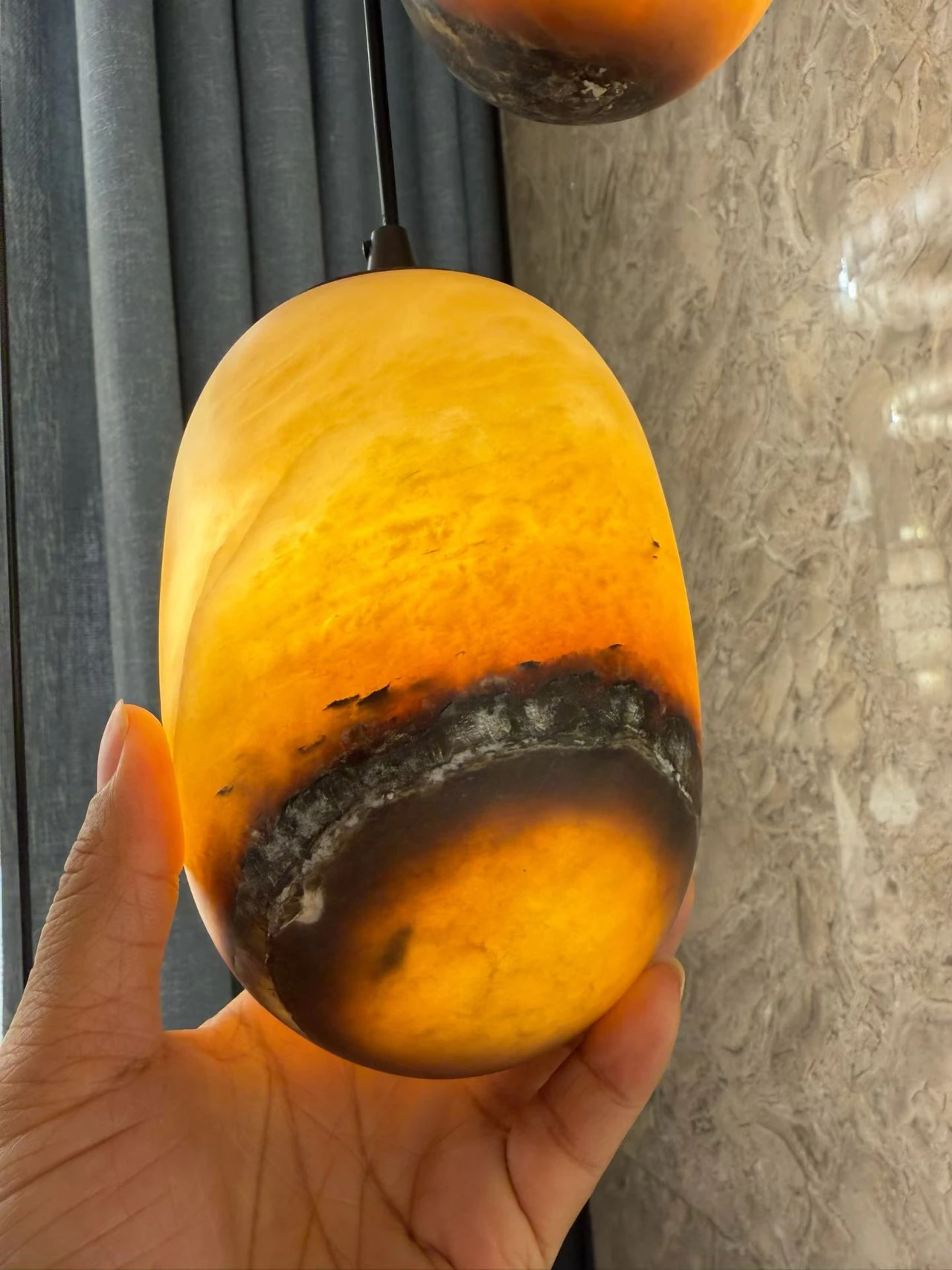 Amber alabaster pendant with a rounded elongated shade and dark stone band