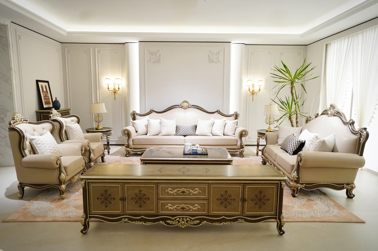 Cream sofas and armchairs with ornate metallic-tone frames, coffee table and console
