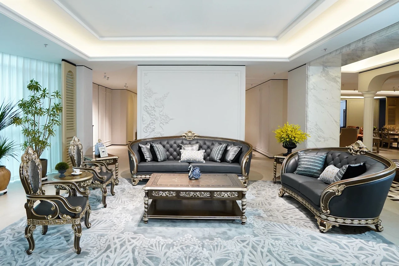 Charcoal tufted curved sofas and matching chairs with ornate gold-tone trim